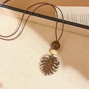Collier pendentif feuille style bohème avec cordon en cuir marron et perles en bois.