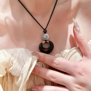 Vue rapprochée détaillée du collier pendentif en résine et bois de style forestier.