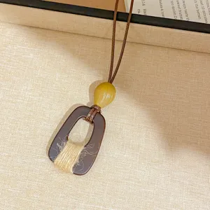 Gros plan détail du collier pendentif en résine style forêt avec corde et cuir.