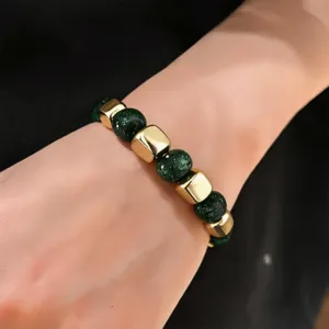 Close-up detail shot of the stylish green resin and gold tone bead bracelet worn on wrist.
