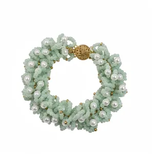 Elegante pulsera tejida de cuentas de semillas y perlas falsas con cierre floral dorado chic.