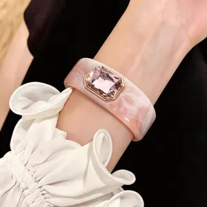 Primer plano detallado del elegante brazalete de resina rosa con un cristal brillante.