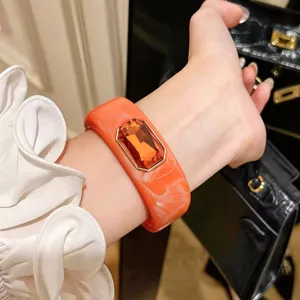 Primer plano de un brazalete de resina naranja vintage con una gran piedra de cristal brillante.