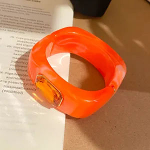 Primer plano detalle del elegante brazalete abierto cuadrado de resina naranja vintage.