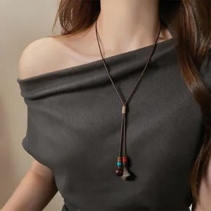 Close-up detail of a vintage ethnic style leather cord necklace with wooden beads and acorn pendant.