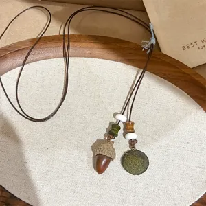 Detailed view of forest style vintage acorn necklace with leather cord and wooden beads.