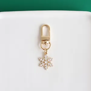Gold metal lobster clasp keychain with a cute white enameled snowflake pendant for lovely bags.