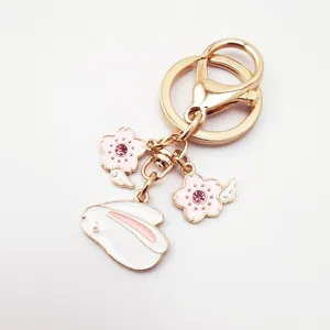 Cute alloy keychain with cute bunny and pink cherry blossom pendants for bag decoration.