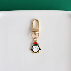 Close-up detail of cute Christmas penguin metal keychain pendant with golden lobster clasp clip.