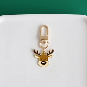Close-up detail of cute cartoon reindeer keychain, gold metal charm pendant for bags.