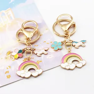 Close-up detail of cute unicorn keychain with colorful rainbow and cloud charms, gold metal.