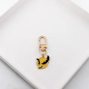 Close-up detail of the metal keychain pendant with bat and moon design, gold alloy.