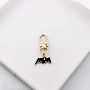 Close-up detail of the cute black bat pendant on a gold alloy keychain, perfect for bag charm.