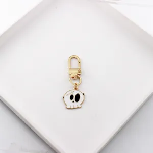 Close-up detail of cartoon skull alloy keychain charm and gold-tone clasp accessory.