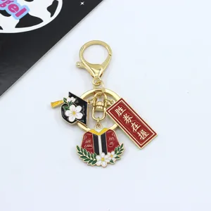 Close-up detail view of a metal graduation keychain featuring cap and gown charms.