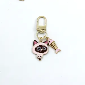 Detail view of the cute alloy siamese cat keychain pendant with pink fish bone.