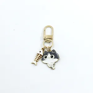 Close-up detail of cute black and white cat keychain with a fish skeleton pendant charm.
