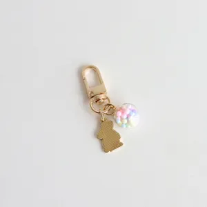 Detailed shot of gold rabbit keyring with colorful ball charm, cute bag accessory and pendant.