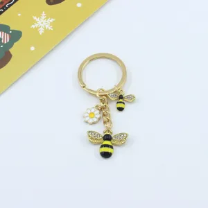 Close-up of gold-tone alloy bee and daisy keychain showing fine enamel and crystal details.
