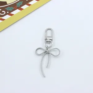 Close-up detail of silver bow keychain pendant, delicate metal bow knot design, close-up shot.