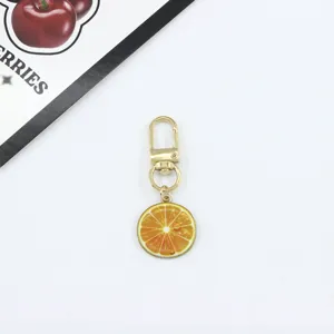 Orange slice metal keychain bag charm pendant detail view, cute fruit design accessory.