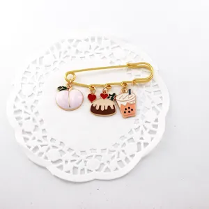 Detalle de broche esmaltado lindo con colgantes de melocotón y té en alfiler de gancho.