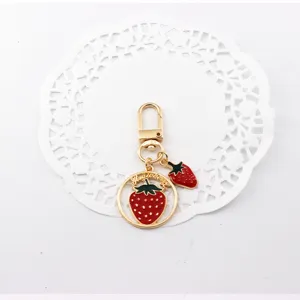 Cute strawberry metal keychain and bag charm, stylish alloy pendant accessory detail shot.