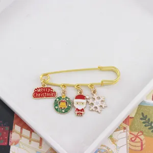 Dettaglio spilla di Natale con graziosi ciondoli in metallo Babbo Natale, ghirlanda e fiocco.