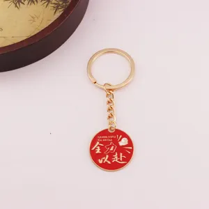 Porte-clés en métal avec pendentif rond rouge et détails de citations motivantes.
