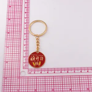 Porte-clés en métal avec pendentif rond en émail rouge et motif porte-bonheur chinois.