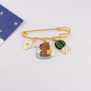 Detailed shot of cute capybara enamel brooch with flower and cactus charms, gold pin.