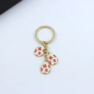 Gold metal keychain with three enamel egg pendants with cute red floral patterns for women.