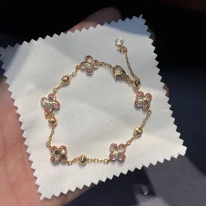 Detailed shot of a gorgeous gold-tone bracelet featuring sparkling pink zirconia flower clover charms.