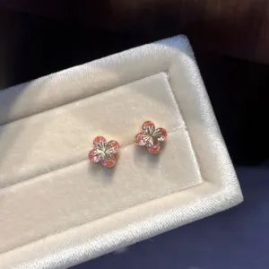 Detailed close-up of pink zircon four-leaf clover stud earrings in a cream velvet box.