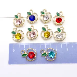 Detailed shot of DIY apple alloy rhinestone pendants with colorful crystals and green enamel leaves.