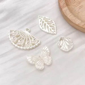 Detailed shot of silver DIY jewelry charms including butterfly, fan, and leaf pendants.
