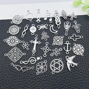 Detail view of assorted antique silver DIY charms, featuring crosses, notes and hollow floral links.