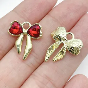 Gold alloy bow charms with red heart rhinestones and hammered texture, perfect for DIY jewelry.