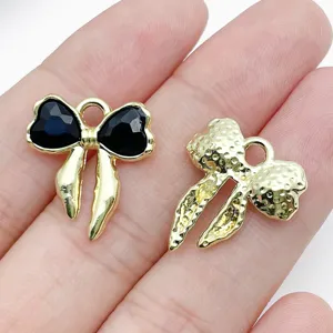 Detail view of alloy bow DIY jewelry pendants featuring black stone and gold textured finishes.