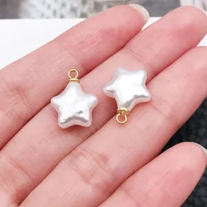 Close-up detail of white star pearl pendant with gold jump ring for DIY jewelry making.
