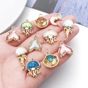 Detailed view of colorful rhinestone jellyfish and cute mermaid tail metal charms for DIY jewelry.