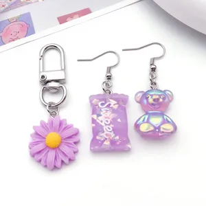 Dettaglio accessorio gioiello fai-da-te in resina viola, con portachiavi margherita e orecchini.