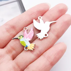 Close-up detail of colorful hummingbird enamel double-loop metal charms for DIY bracelets.