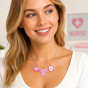 Close-up detail of a gold chain necklace with pink medical themed charms worn by a model.