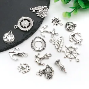 Close-up detail of vintage nautical DIY metal charms including anchors, ship wheels and globes.