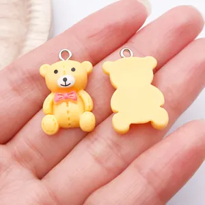 Detailweergave van een schattige gele hars teddybeer bedel met roze strik voor eigen sieraden.