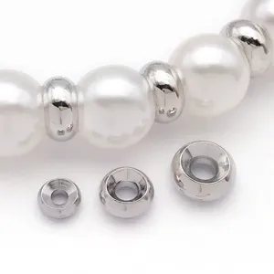 Gros plan de perles intercalaires métalliques et perles blanches pour bijoux et bracelets DIY.