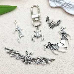 Close-up detail of retro silver hollow bat wings and cross charms for DIY jewelry making.