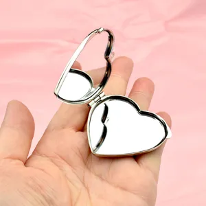 Vista dettagliata dello specchietto tascabile pieghevole a forma di cuore argentato.