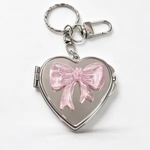 Detailed view of the cute pink glitter bow heart mirror keychain, elegant silver metal charm.
